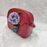 Purple pompom on a red faux leather sling bag