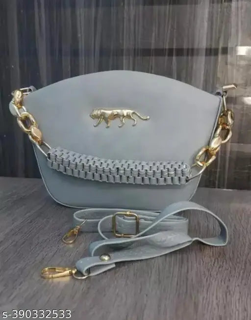 Gray purse with a lion charm, featuring a long chain strap and small shoulder bag style