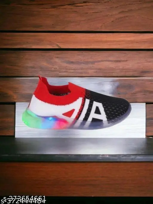 The image depicts a single, vibrant red MUKU LTPS sneaker. It features a white outsole with a colorful design and is set against a blurred wooden background. Please note that the specific model or brand of the sneaker is not discernible from this angle