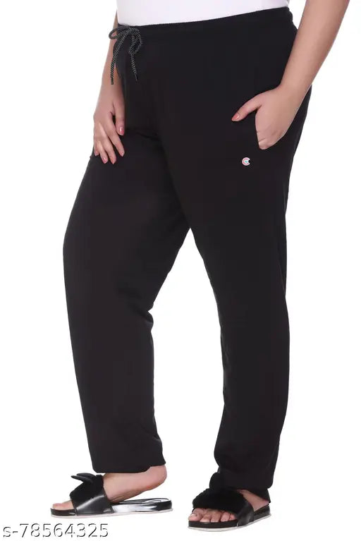 The image displays a person wearing black cotton track pants, which appear to be a plus size style for women and girls. The pants feature elastic drawstrings on the sides and cuffs at the ankle