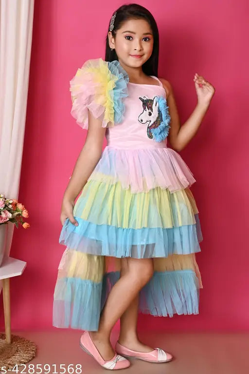 A girl wearing a multicolored rainbow unicorn dress with frilly sleeves and ruffled bottom