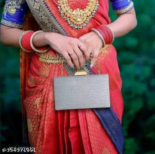 Silver metal folding clutch, likely a bride's purse or fashionable clutch bag, shown in a young woman's hands