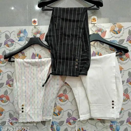 White children's pants with button closure, hung together on hanger