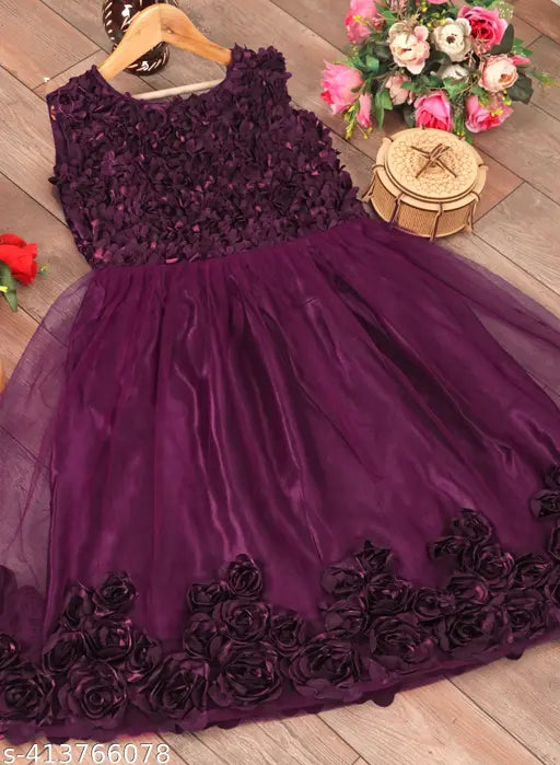 The image displays a sleeveless purple dress with lace details. It has a flared skirt and a sweetheart neckline, featuring ruffled edges and what appears to be a sheer overlay. The dress is displayed on a wooden surface