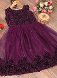 The image displays a sleeveless purple dress with lace details. It has a flared skirt and a sweetheart neckline, featuring ruffled edges and what appears to be a sheer overlay. The dress is displayed on a wooden surface