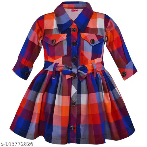 This is a charming multicolored dress in shades of blue, red, green, and yellow, adorned with contrasting white piping details. It features a collared neckline, adding a touch of elegance, and is fastened with a cute little bow tie at the waistband. The dress has a vibrant kraft background and could be made from cotton material
