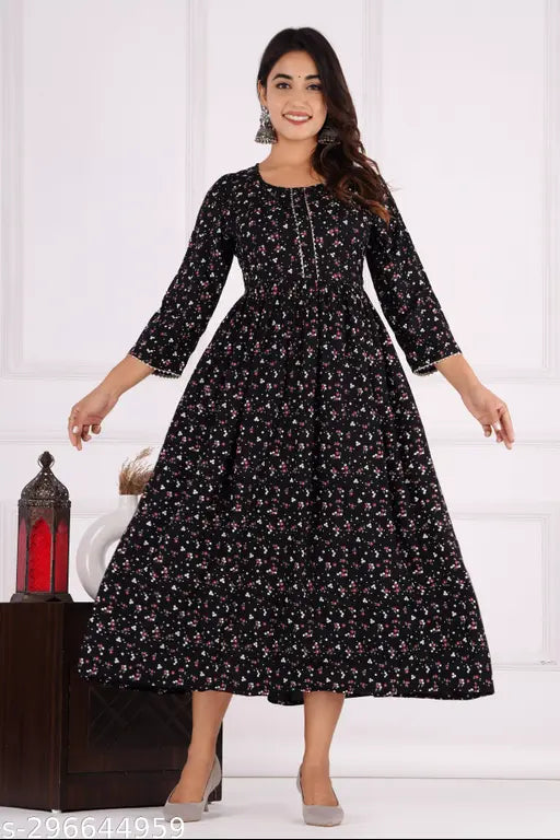 The image features a woman wearing an "Amazing Gathered Kurti." It is a long-sleeve dress with a high neckline, and it appears to be made of a fabric that has small speckled patterns. The dress is knee-length and features a V-neck design at the waist. The sleeves are gathered just above the elbows, and there are no visible pockets or embellishments on the dress. The woman is standing in an indoor setting, with a table visible behind her