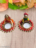 Small, colorful ceramic tea light candle holders decorated with Indian puppet design. Contains a small white candle