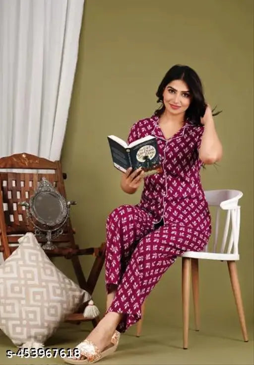 A person in a night suit, reading a book. The attire appears comfortable and cozy, suitable for a quiet evening at home. It features a rayon print pattern, which adds a touch of color and style to the outfit. Comes with matching bottoms, perfect for a coordinated look. Includes a top and bottom set, providing options for wearing separately or together. The night suit is designed to keep its wearer warm and comfortable throughout the night