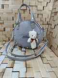White leather sling bag with multiple pockets and a teddy bear charm