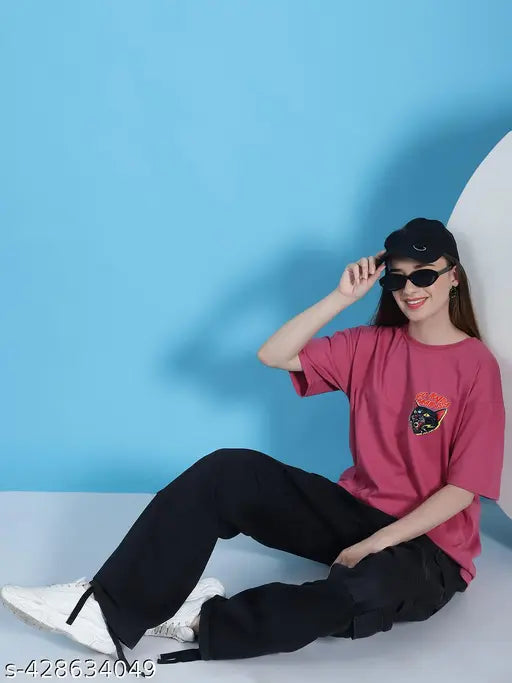 A person is wearing a pink cotton oversized casual t-shirt with a dark print
