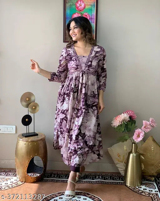 Woman in a purple and white floral long dress standing by a wall