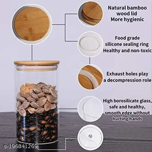 A set of four transparent glass jars, each with a natural bamboo wood lid, used as home and kitchen storage containers
