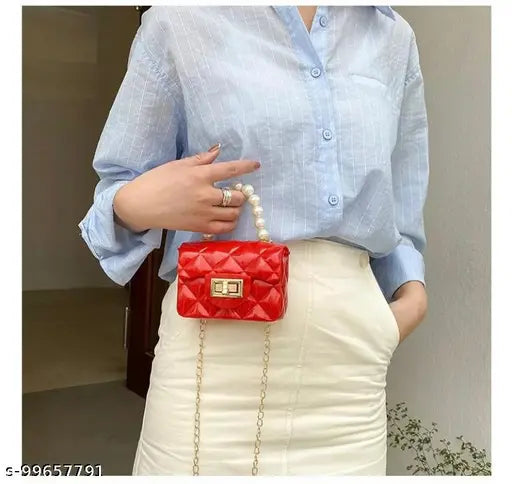 Silicone sling bag with side shoulder strap, suitable for travel, party, and casual occasions. Black design with gold hardware and two pockets. Can be worn as a crossbody or on the shoulder