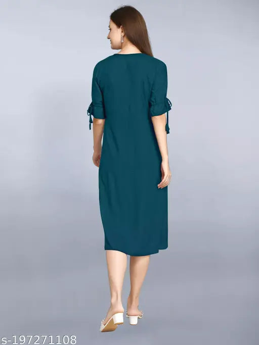 A person standing, wearing a dark blue long-sleeve dress with a high collar and frill sleeves