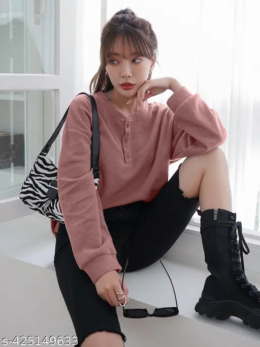 A kid's waffle round neck top in oversized style, with a long sleeve, featured on a woman wearing black boots and shorts