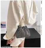 Small rhinestone crossbody purse with silver chain strap, pearl embellishments on a black background