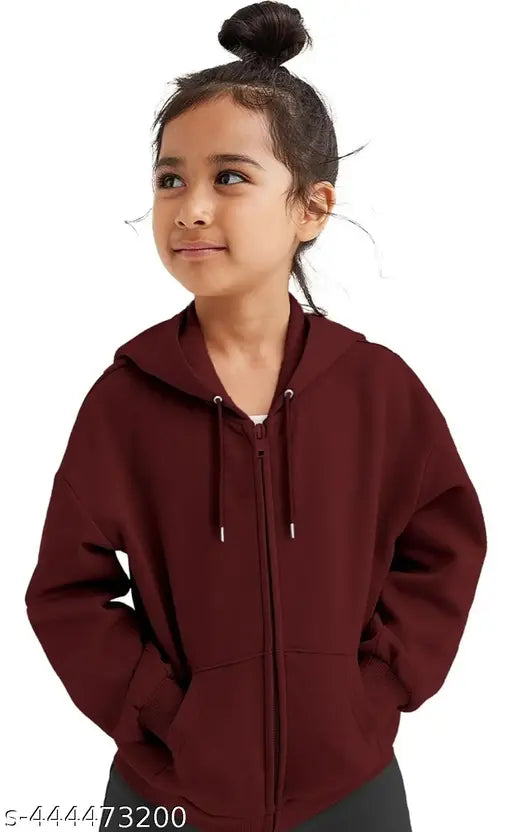 The image shows a young child wearing a red shirt with a white hood and zipper front. The child has dark hair tied up in a bun and is smiling at the camera