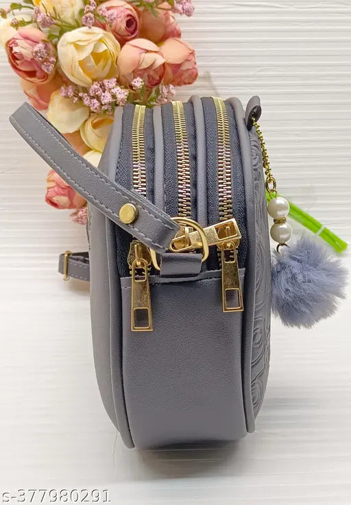 Grey women slingbag with gold zippers and fluffy pom pom details