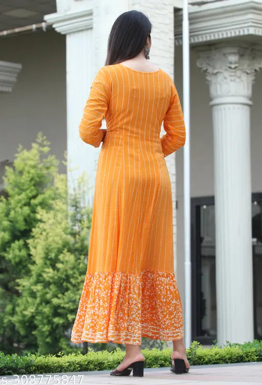 Woman standing in front of pillars, wearing an orange traditional kurta with embroidery
