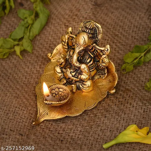 Gold metal Ganesh statue on pipal leaf with diya, decorative home office gifting item (3cm). Intricately crafted Hindu deity ornament for special occasions, light up space with unique design and diya holders. Made in India