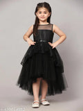 A black, floor-length dress with ruffled sleeves and a ruffled hem on a little girl posing