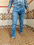Man standing in front of tiled wall, wearing blue distressed denim jeans with rolled up cuffs and a faded wash