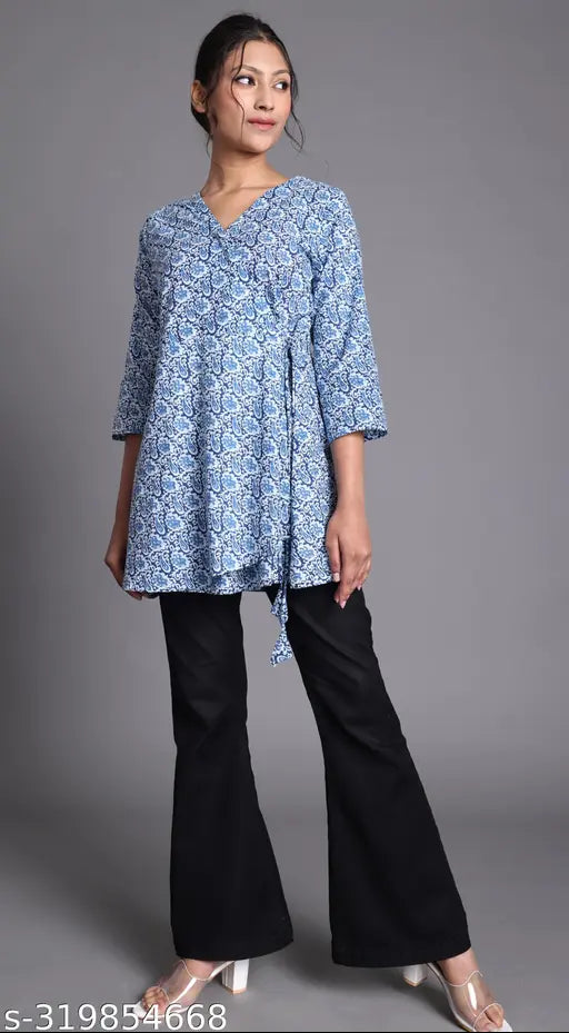 A woman wearing a long-sleeved, knee-length angrakha with flared pants and a deep V-neckline, featuring blue and white print on a solid navy background