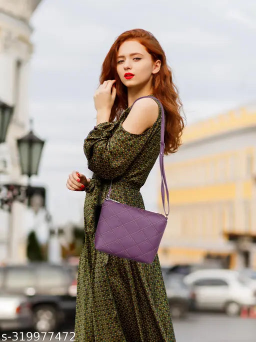 A woman wearing a red blouse, standing outdoors with buildings in the background. She carries a dark purple slingbag over her shoulder, which appears to have multiple pockets and compartments
