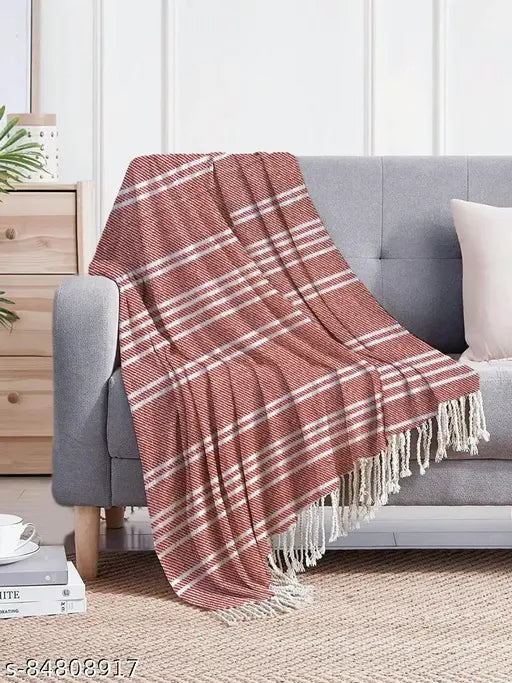 Red fringe blanket with a white pillow and wall behind it