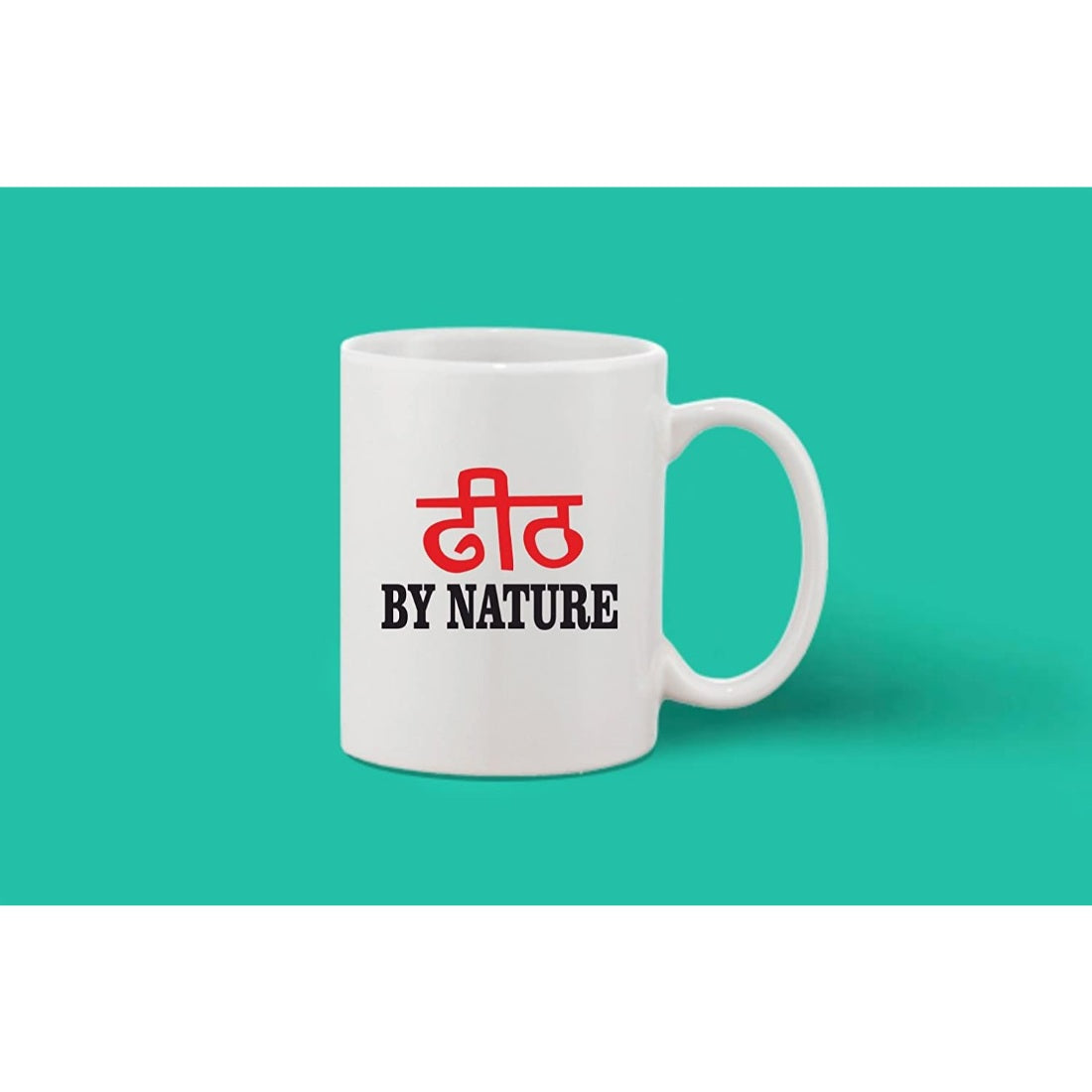 A printed white ceramic coffee mug, likely handmade, with a red phrase reading "BY NATURE" in Hindi script on it