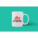 A printed white ceramic coffee mug, likely handmade, with a red phrase reading "BY NATURE" in Hindi script on it