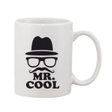 A white ceramic coffee mug with a printed character wearing glasses and a fedora, reading "Mr. Cool" in black text, set against a light background, likely indicating that this is a novelty item or merchandise related to a themed cafe or retro-style coffee shop